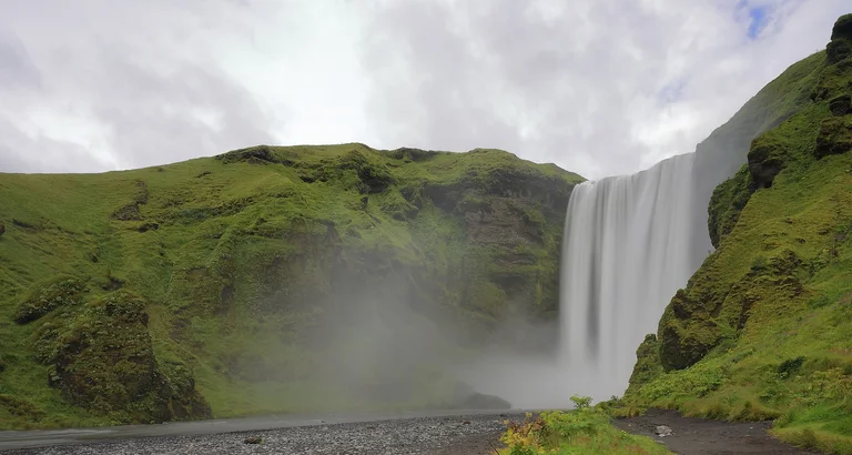 Skógafoss waterfall beneath green cliffs, Iceland