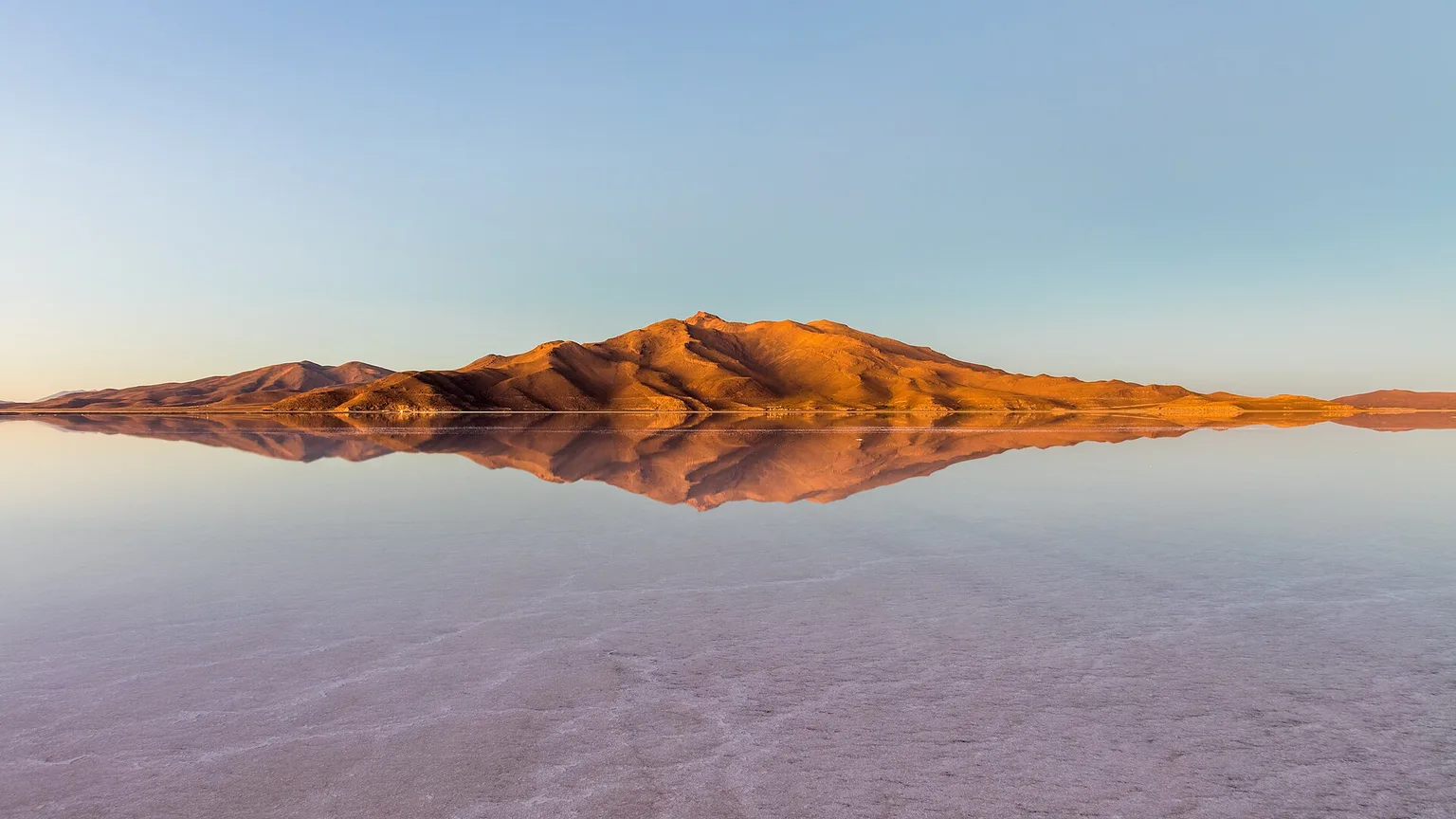 Golden mountains reflected across the flooded Salar de Uyuni, Bolivia
